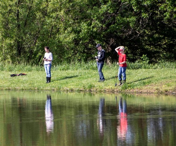 Three people fish at pond