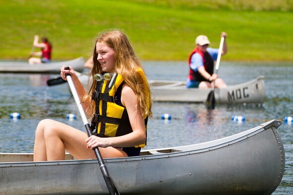 Girl canoes on lake during Girls Camp