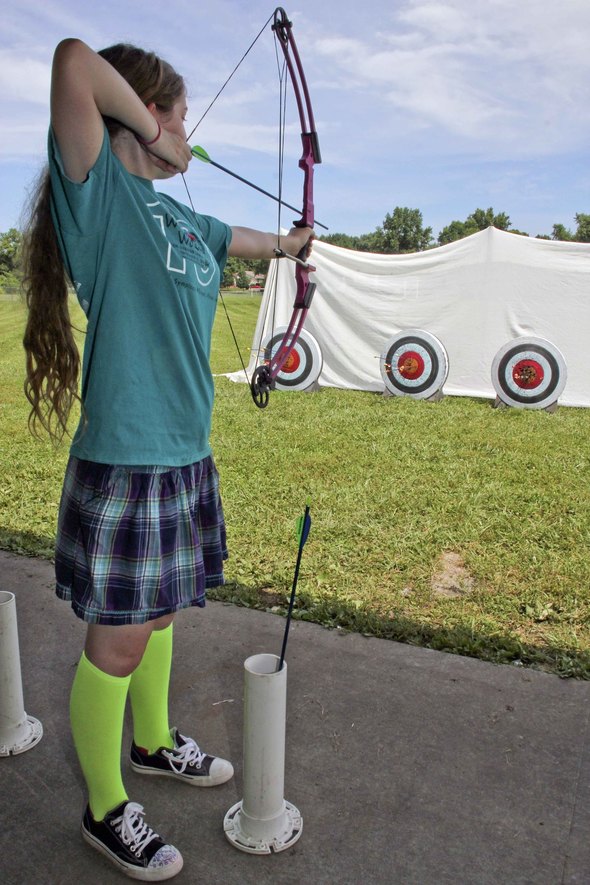 Girl shooting a bow at a target.