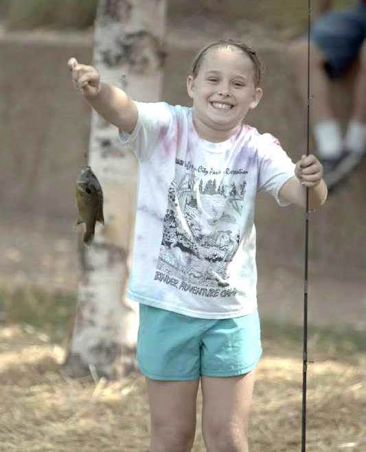 Little girl holding up a fish she caught.