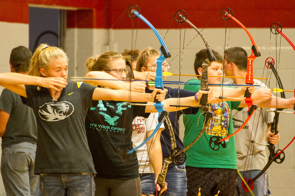 Students shooting bows in gym class.
