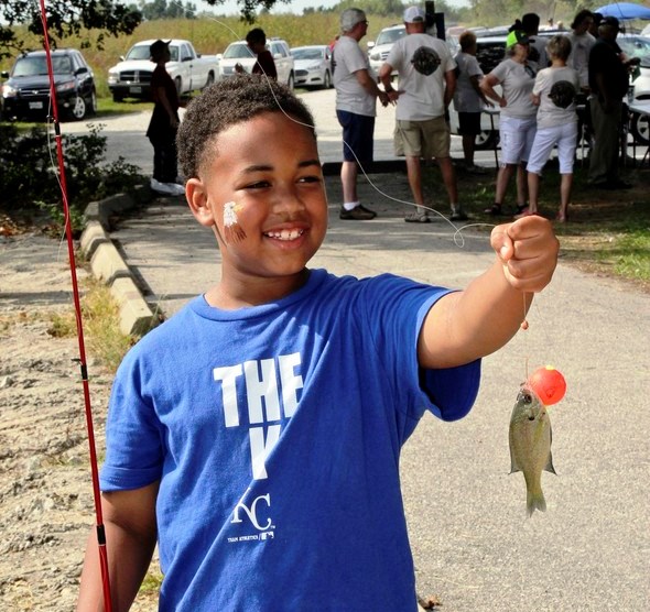 A boy holds a small fish he caught at Family Outdoors Day