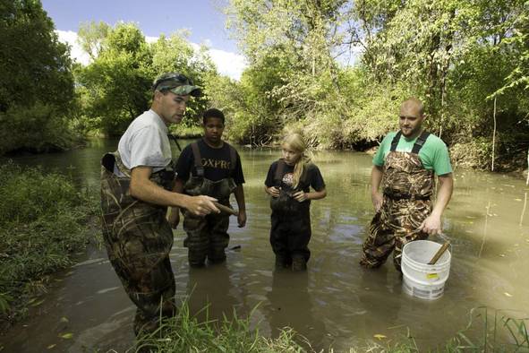 People standing in the water learning about trapping.