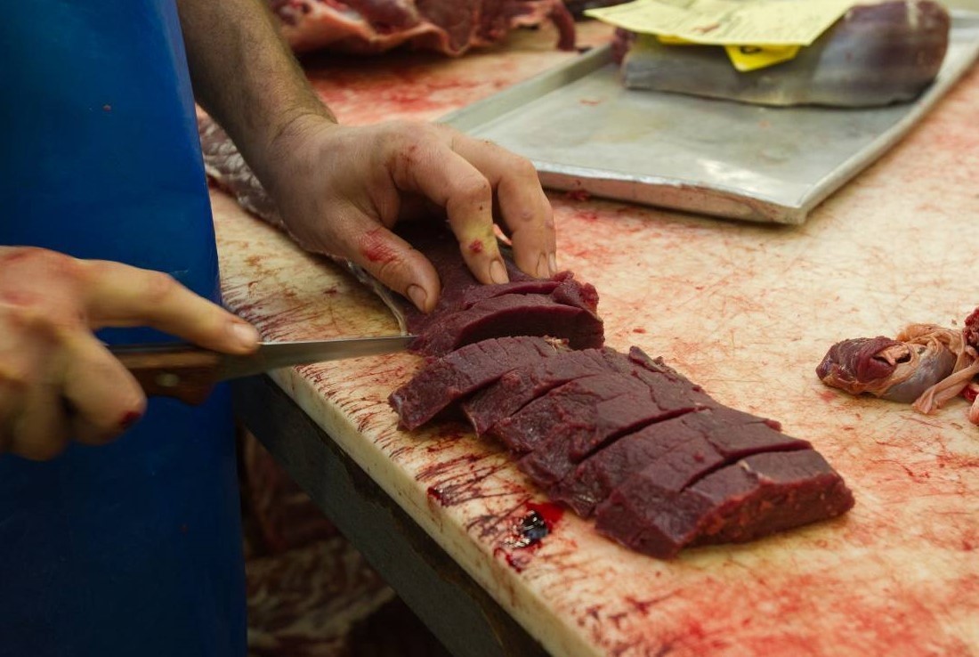 Hunter cutting venison meat