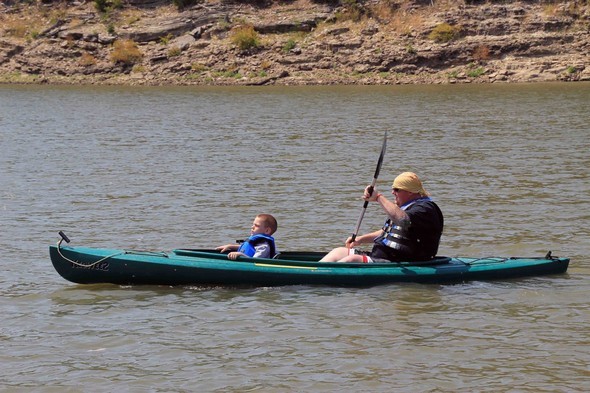 A father and son kayaking on a lake.