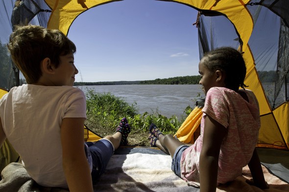 Kids sit in a tent while camping