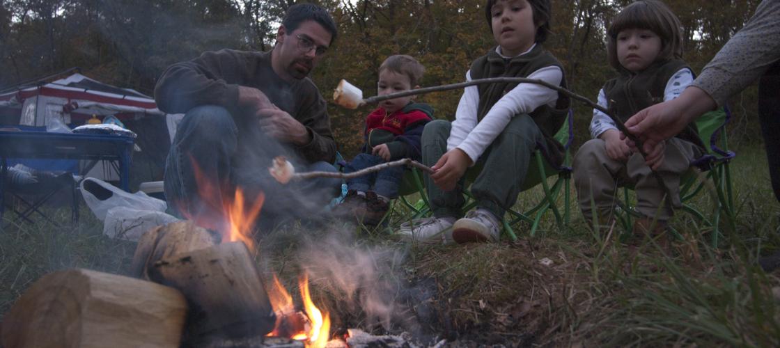 A family toasts marshmallows over a camp fire.