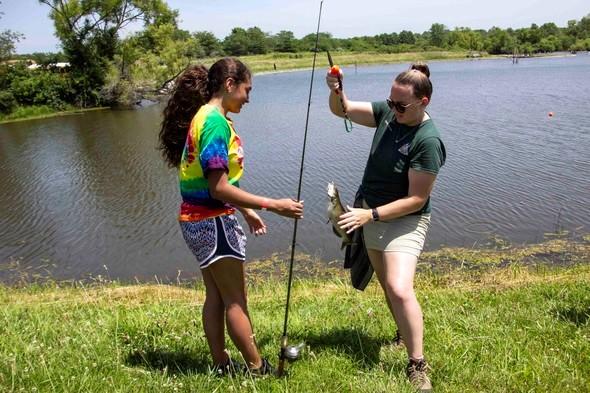 MDC staff takes a fish off a line for a teenager