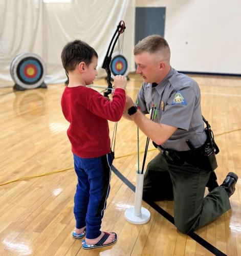 Agent Kyle Dick helps young boy learn archery
