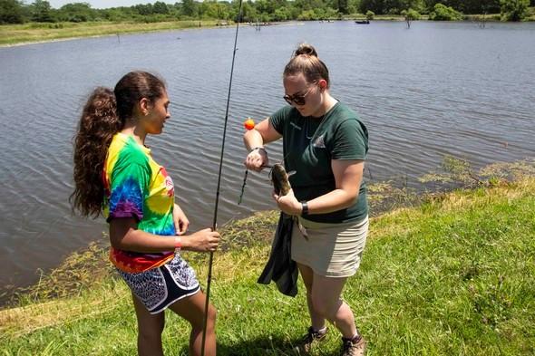 MDC staff member helps unhook a fish from teen's fishing line