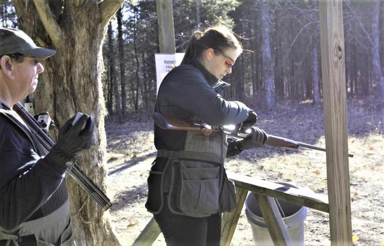 An MDC conservation educator shows a man how to shoot a shotgun