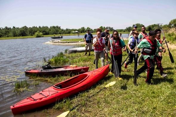 Young explorers carry their oars after kayaking during Outdoor Skills Day