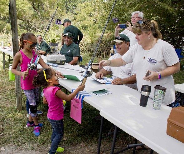 Children picking up fishing rods from a table at Family Outdoors Day