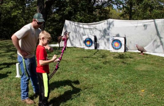 guy teaching archery to kid