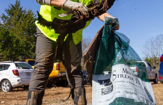 Woman picks up trash along watershed