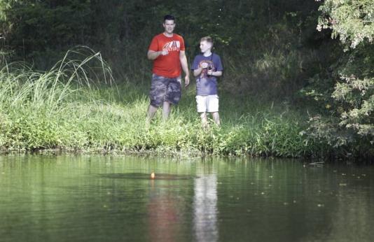 Father and son fish at pond