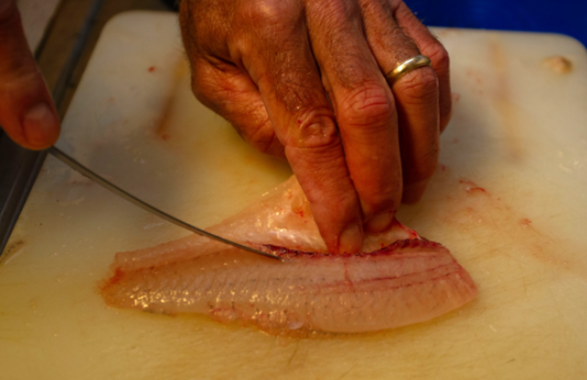 Man cuts fish filets on cutting board