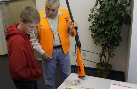 Hunter ed instructor helps boy with firearm safety