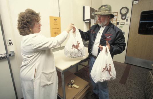 A hunter offers a bag of venison to a food pantry worker