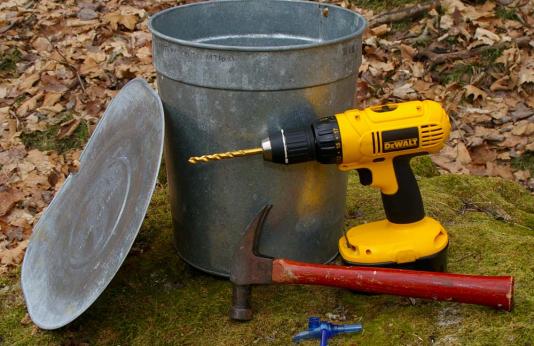 Tapping supplies for maple sugaring: drill, hammer, tap and container