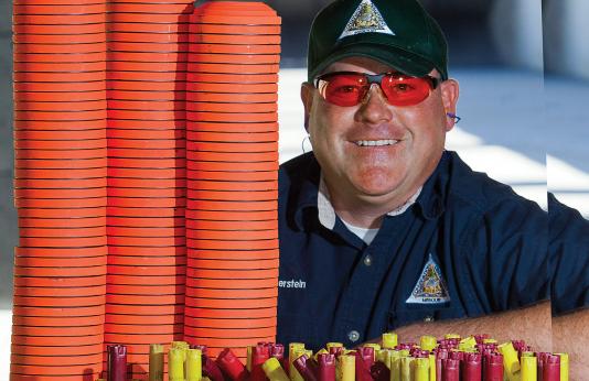 Man posing with a big stack of clay pigeons and shotgun shells