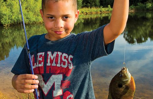 A young boy with a bluegill he has caught.