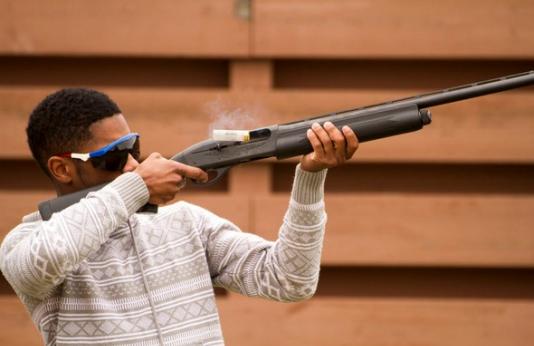 A man shooting a shotgun.