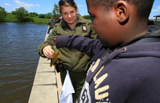 MDC Conservation agent helping a little boy with his fish.
