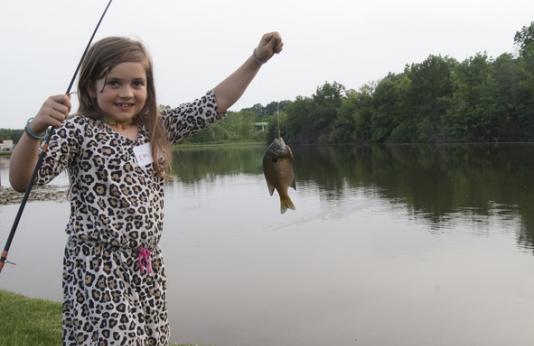 Little girl holding up a fish.