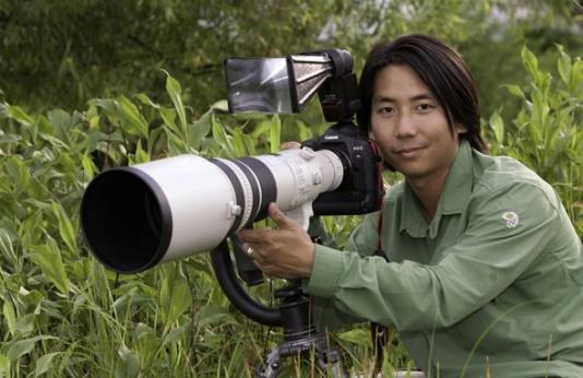 MDC photographer Noppadol Paothong poses with his camera in nature.