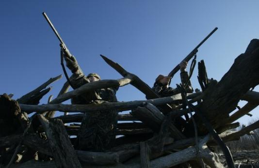 two hunters shooting from waterfowl blind