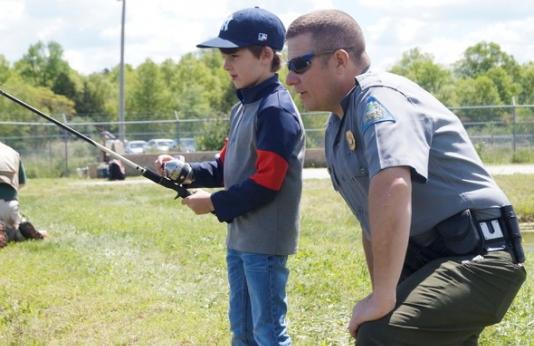 A conservation agent helps a young angler fish at an MDC pond.