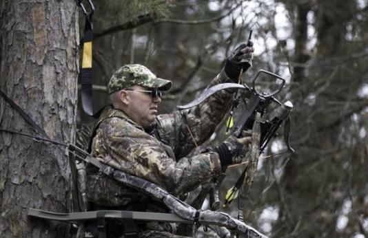 A hunter loads his crossbow in the woods.