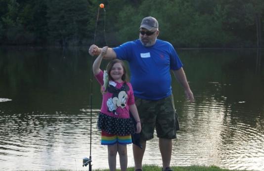 A little girl shows off her catch with her dad.