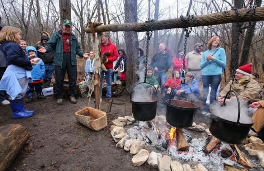 people standing around fires with pots as they process maple sap into syrup 