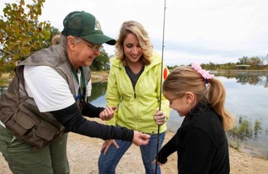 MDC staff teach a mother and daughter how to fish.