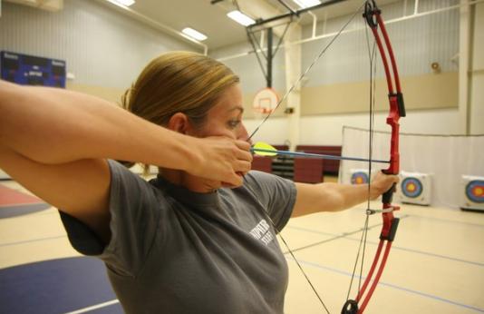A teacher tests her skills at an archery instructor training class.