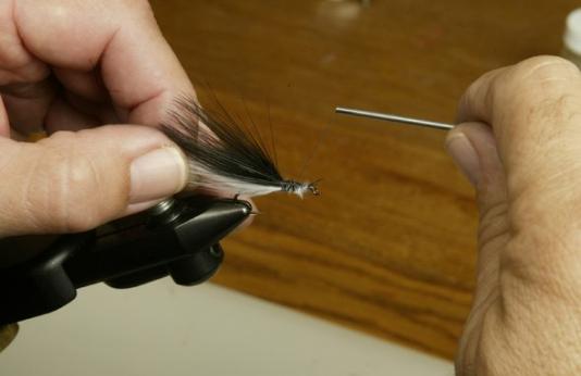 closeup of a person's hand tying a fishing fly